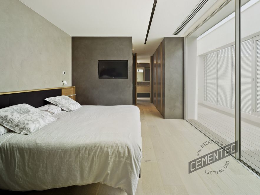 Reforma con microcemento y madera en dormitorio donde se combina el suelo de tarima natural con el microcemento Cementec Estándar en las paredes.