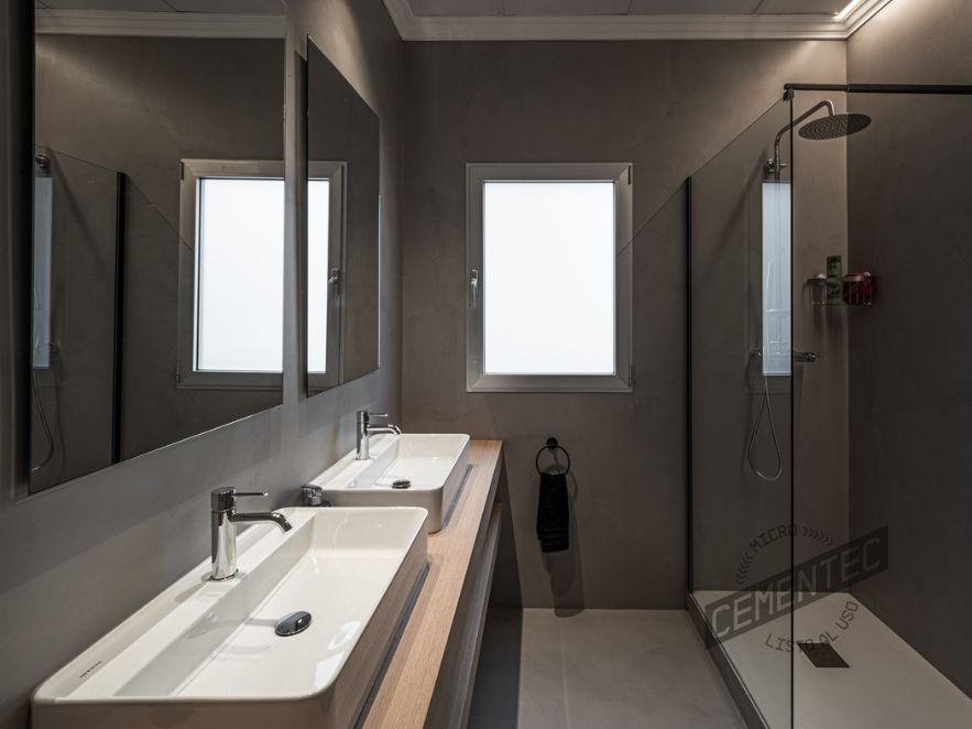 Grey bathroom in which one of our microcement showers with glass panel was installed. 