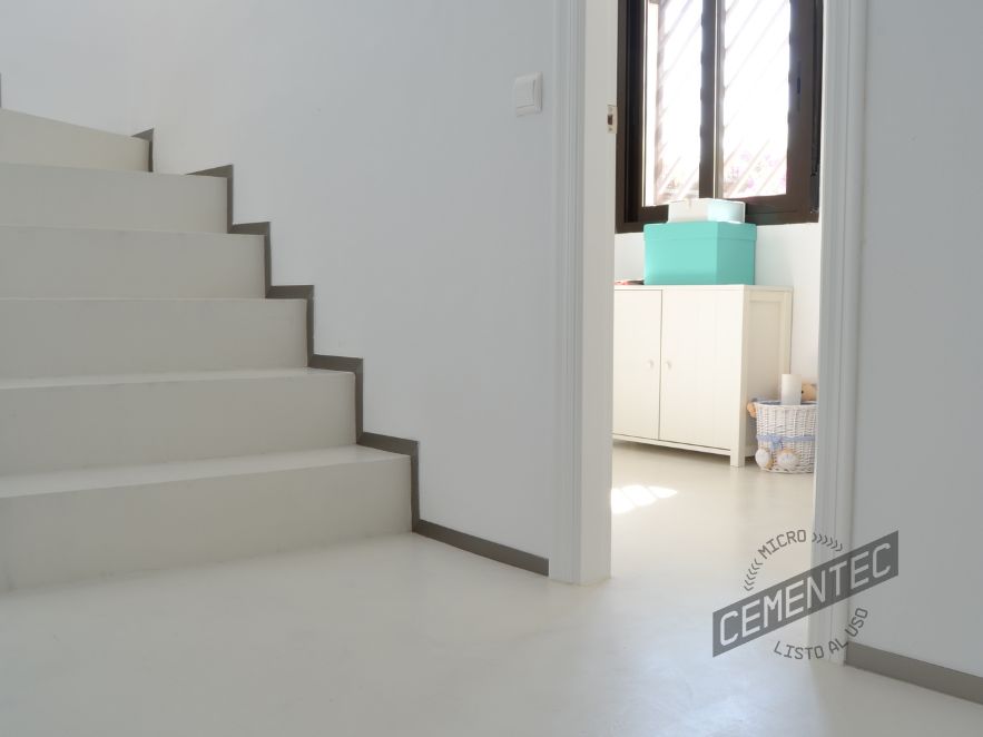 Microcemento de color blanco en suelo y escalera de vivienda desde donde se observa la habitación infantil.