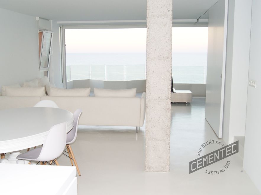 Sala de estar con microcemento blanco de Cementec aplicado en las paredes y en el suelo, así como muebles de color blanco.