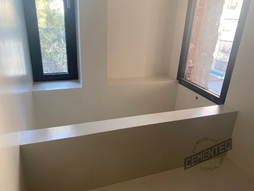Microcement bathtub with two large windows that provide plenty of natural light.