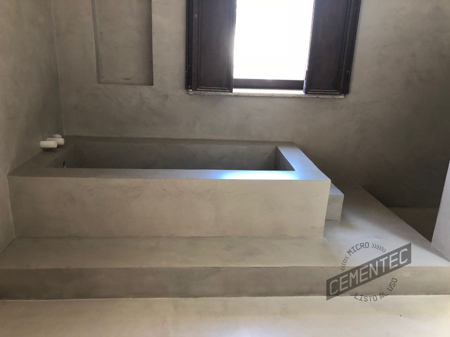 Double-height microcement bathtub in bathroom. 