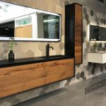 Bathroom frontage with wooden furniture, horizontal glass and microcement on the floor as an example of microcement and wood bathrooms.