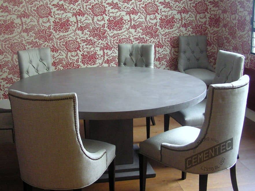 Microcement dining room table with chairs around it, wall with chromatic wallpaper pattern and parquet floor.