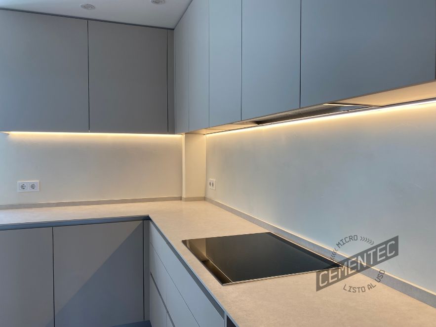 Detail of kitchen front with white microcement and LED lights, finished by Cementec.