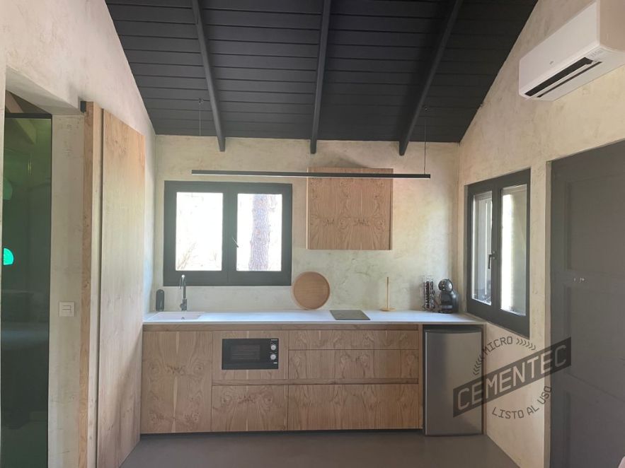 Efficient layout of microcement kitchen with wood and white details.