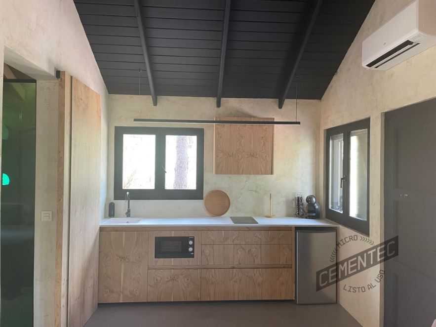 Distribución eficiente de cocina de microcemento con detalles en madera y blanco.