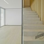 Imagen frontal de salón con escaleras de microcemento y madera en el suelo y en los acabados de la pared de la escalera.