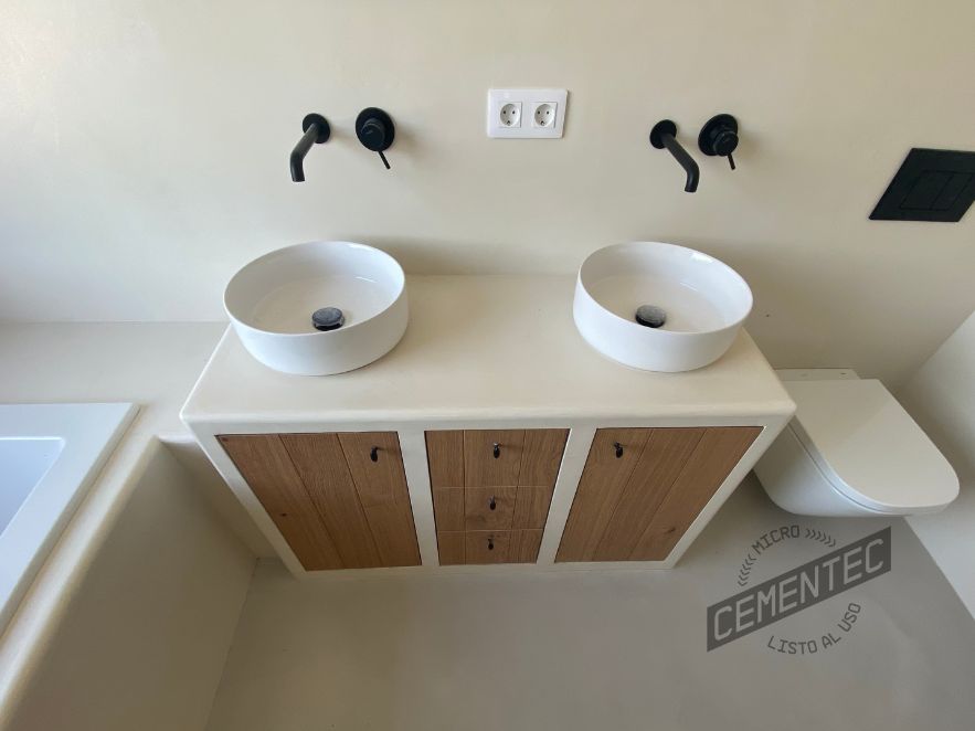 Baño microcemento blanco combinado con mobiliario en madera.