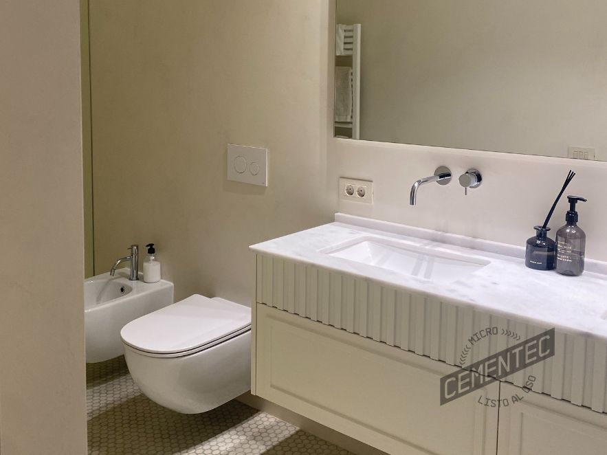 Baño microcemento blanco en estilo minimal con encimera de mármol.